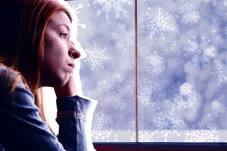 A forlorn-looking woman stares out the window at snow.